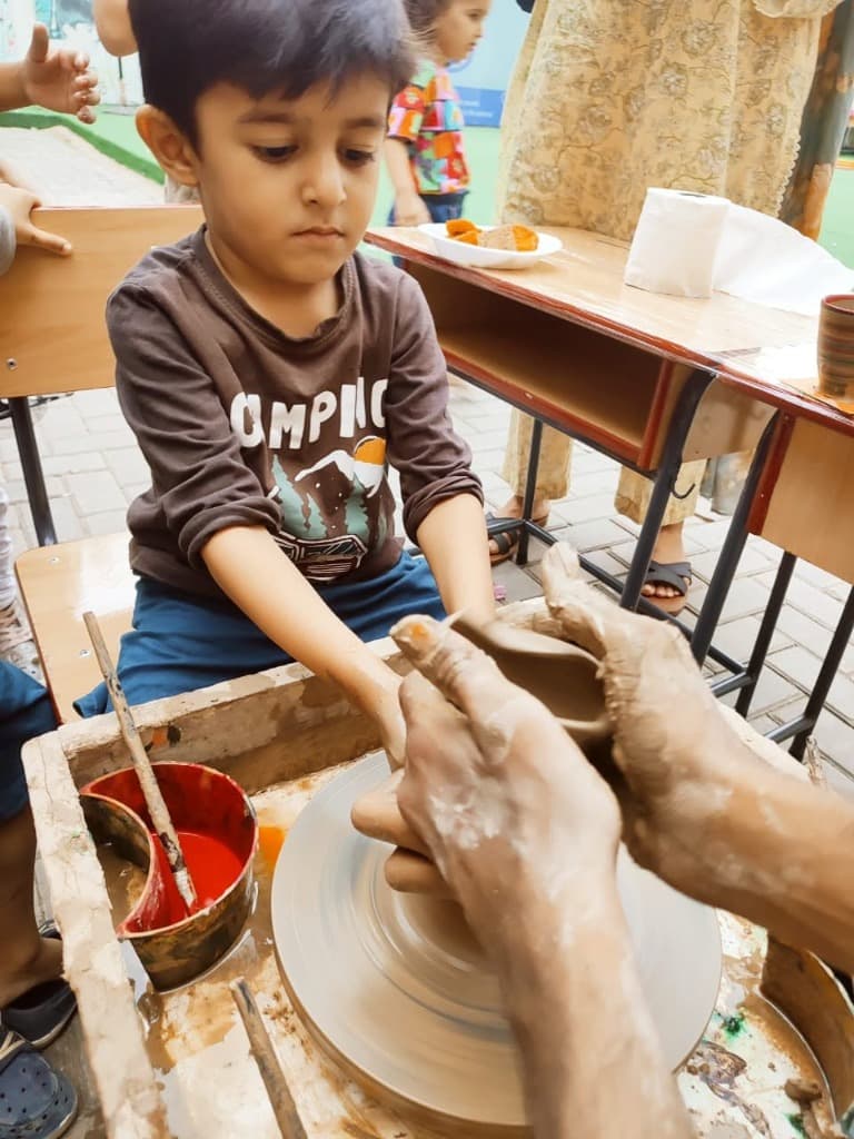 Artisan coaching child on wheel